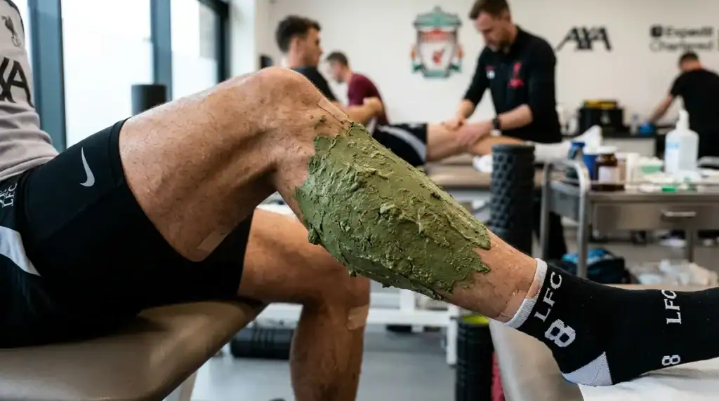 Cataplasme d'argile verte sur le mollet d'un footballeur pour la récupération musculaire après le sport.