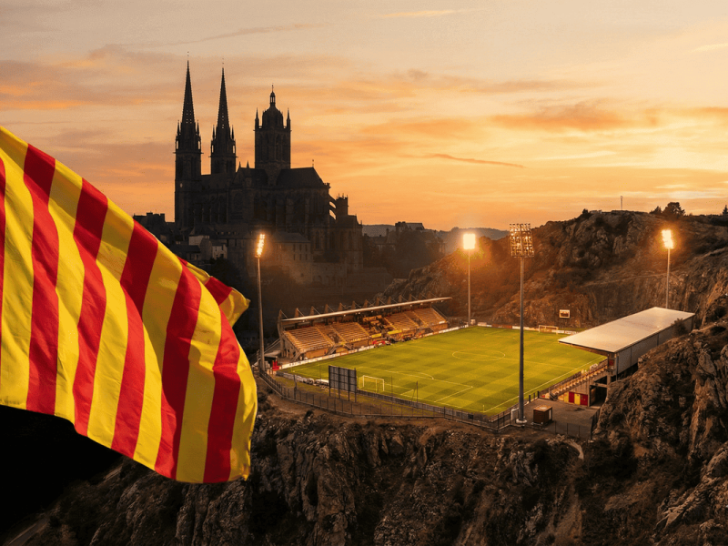 Stade du Rodez Aveyron Football illuminé au pied de la cathédrale de Rodez avec un drapeau Sang et Or.