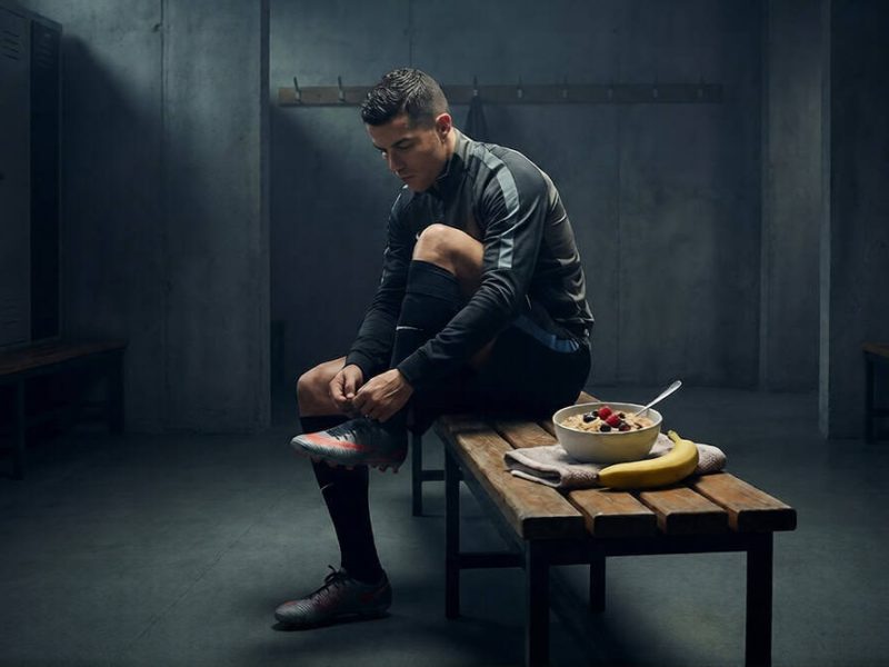 Footballeur se préparant dans les vestiaires avec un petit-déjeuner sain posé sur le banc.